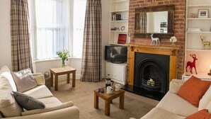 A living room with a fireplace, two sofas, a coffee table, and a television. - Jutes House Exeter (Exeter)