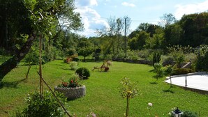 Un jardín bien cuidado con un camino de piedra, un columpio y una estructura circular de piedra.