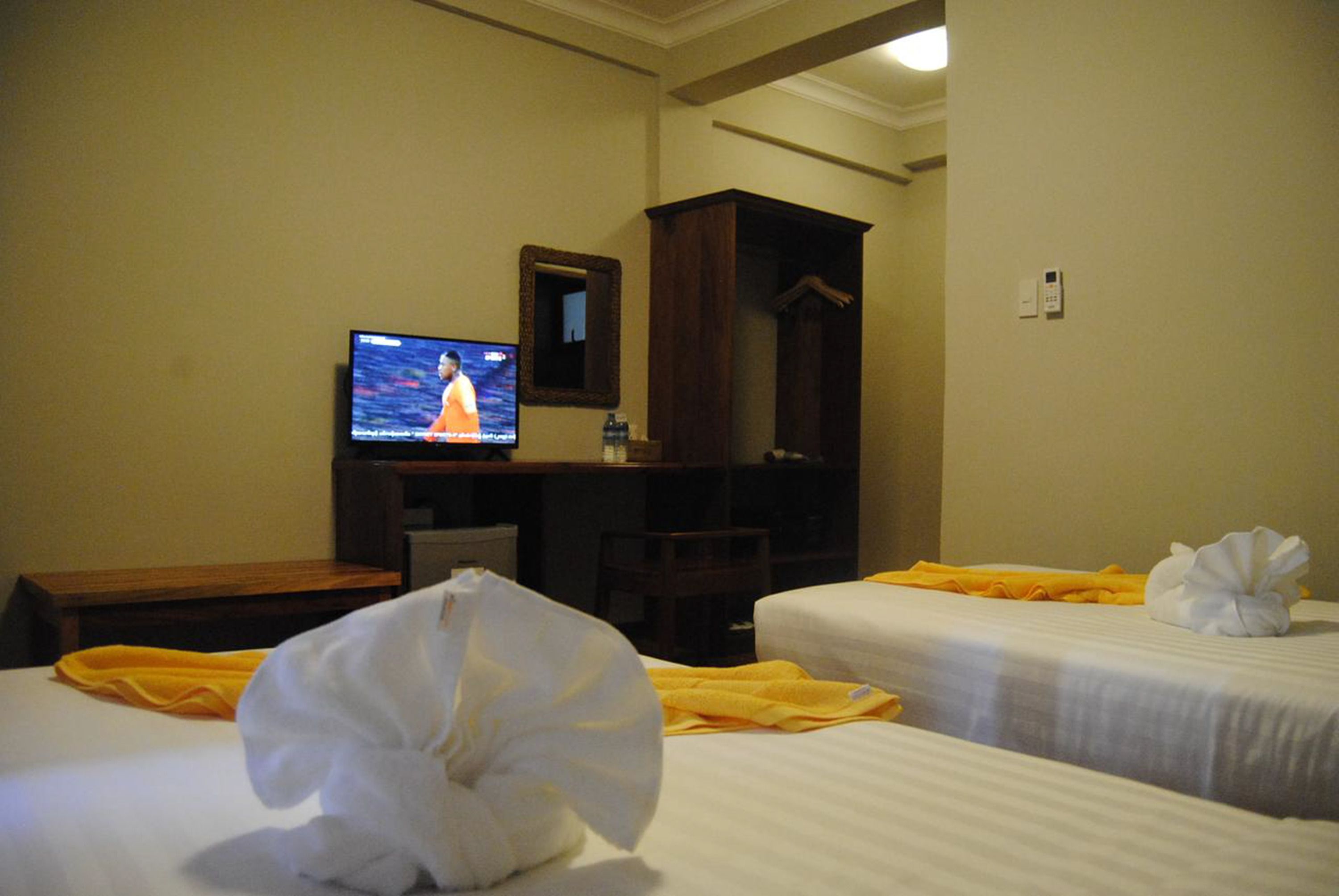 A hotel room with two beds, a television, a desk, and a wardrobe.
