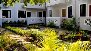 Un cortile con giardino, edifici bianchi con numerose finestre e condizionatori.