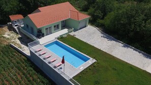 A two-story building with a swimming pool, a covered patio, and a flagpole. - Holiday House 4M (Podbablje)