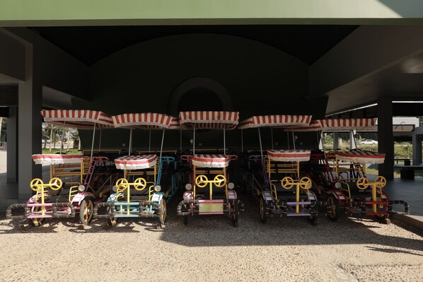A row of vintage carriages with striped canopies parked under a covered area.