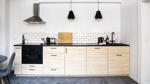 Una cocina moderna con horno negro, armarios de madera, encimera negra y dos lámparas colgantes.