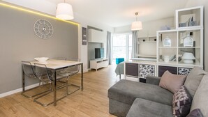 A modern living room with a dining area, a sofa, a TV, and a bookshelf. - Super-Apartamenty Love Deluxe (Poznan)