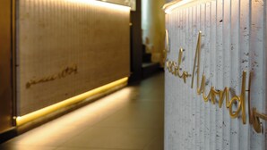 A reception desk with a sign that reads "book now!" in a modern interior with a wooden floor and a glass partition. - LUX suites in Roma (Rome)