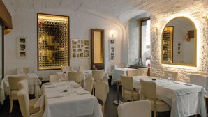A restaurant with white walls, a wine rack, and tables set for dining. - LUX suites in Roma (Rome)