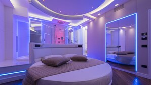 A modern bedroom with a large bed, a glass shower enclosure, and a mirrored wall. - LUX suites in Roma (Rome)