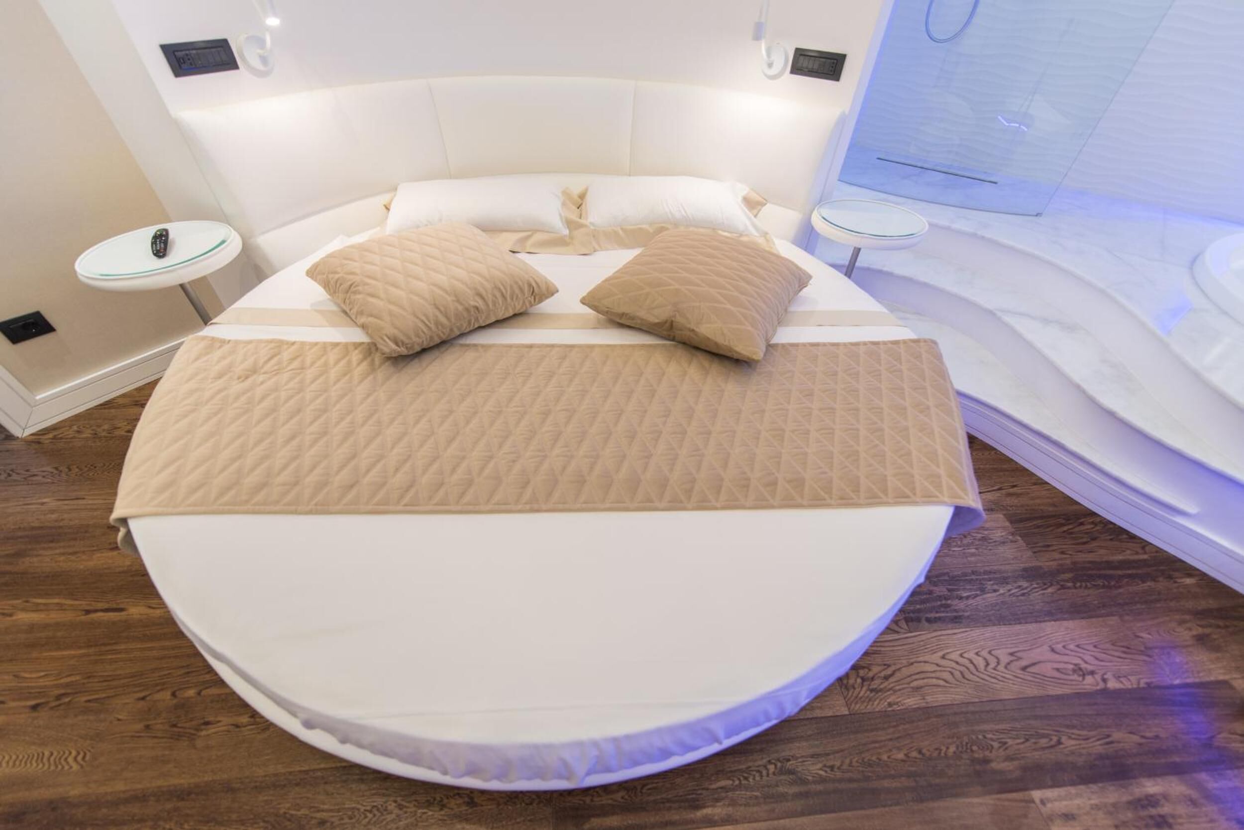 A modern bedroom with a curved bed, a bedside table, and a small round table.