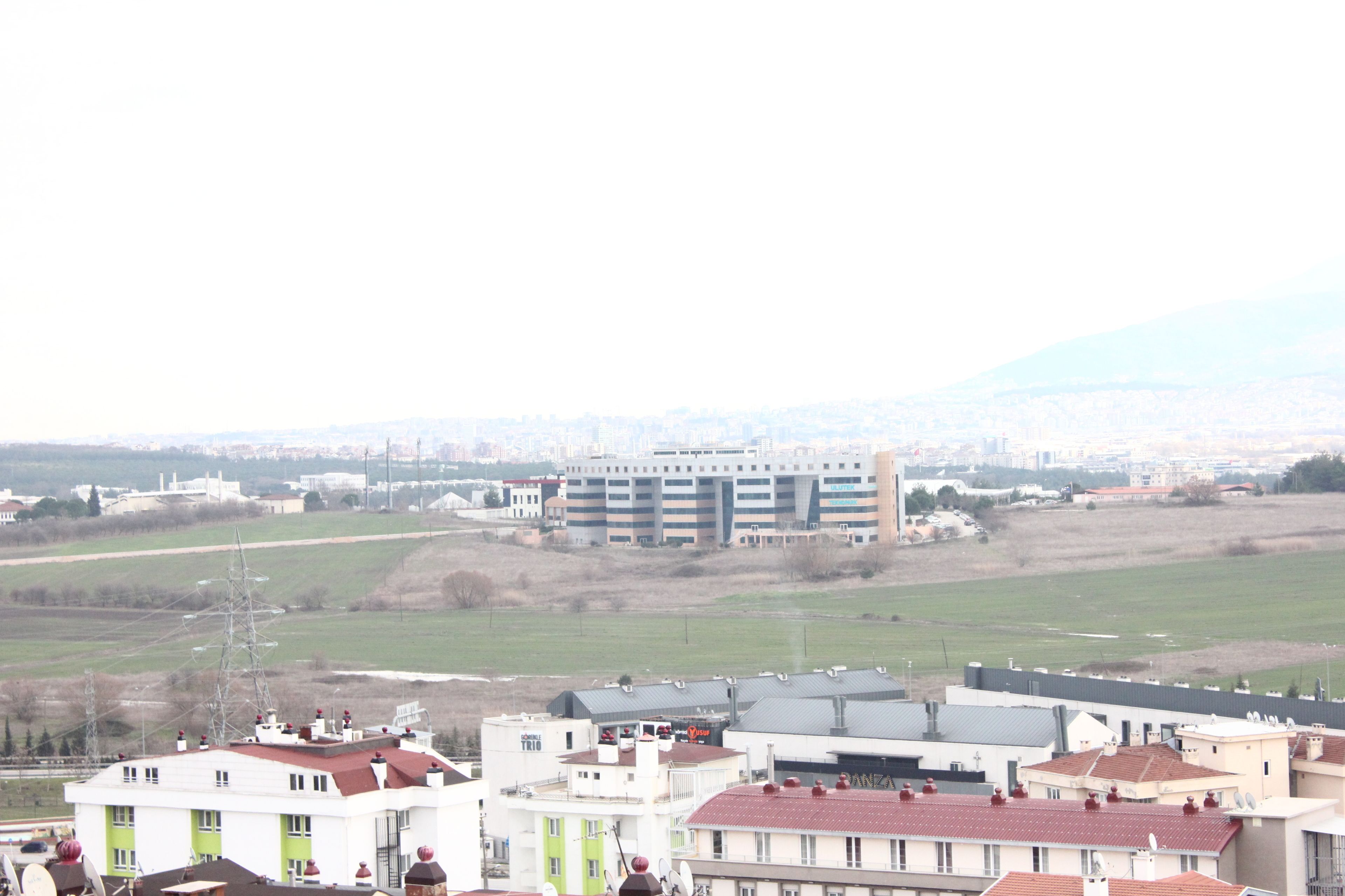 Ein Wohngebiet mit Gebäuden, darunter ein mehrgeschossiges Haus mit flachem Dach und ein kleineres Gebäude mit rotem Dach.