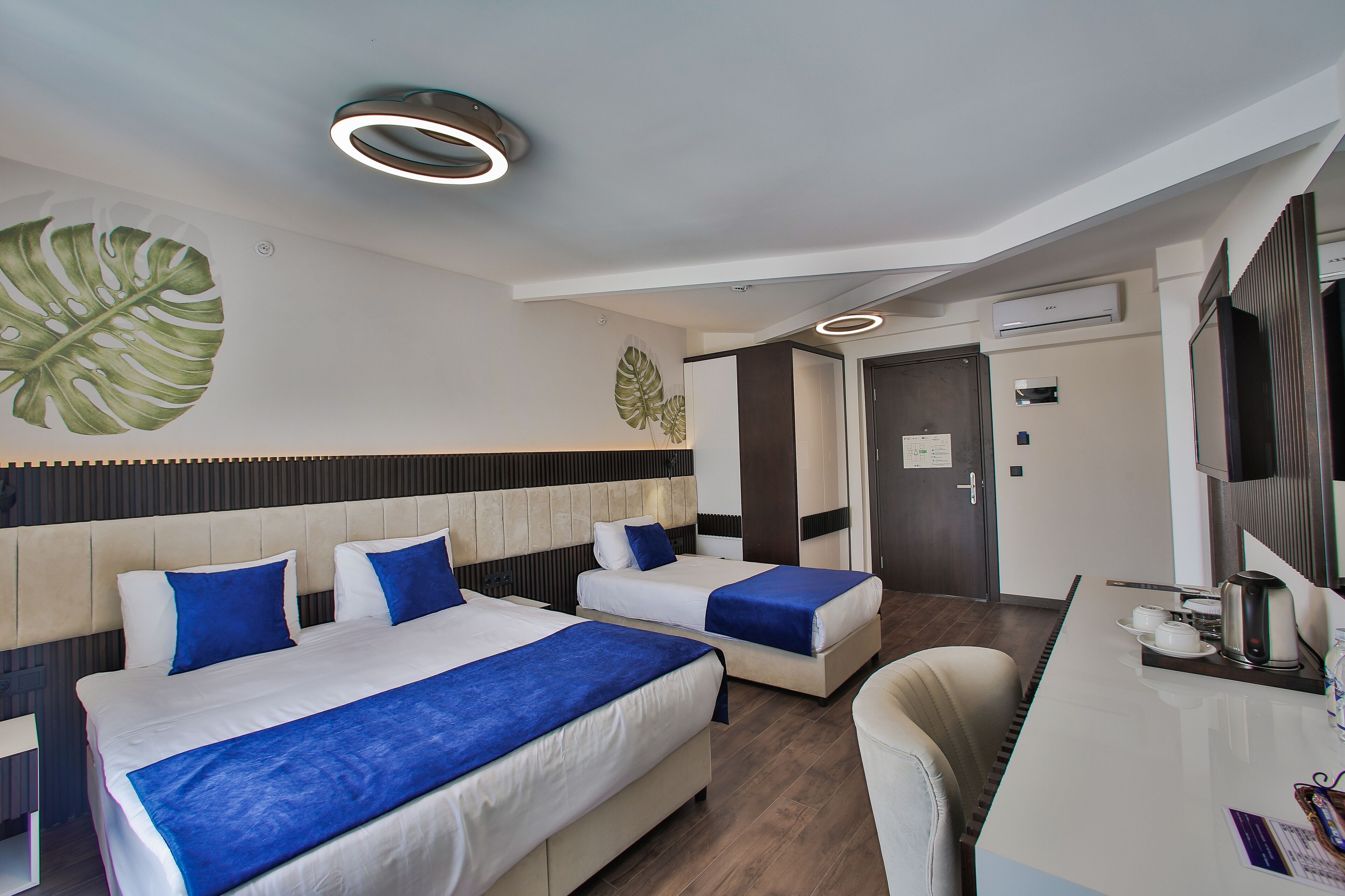 A hotel room with two beds, a desk, and a chair.
