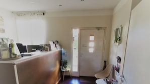 A reception area with a desk, chairs, a small plant, and a door with a sign. - Hotel Restaurant Franziska (Straubing)