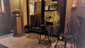 A hotel entrance with a sign reading "Franziska Hotel Restaurant." There are two outdoor tables and chairs, a potted plant, and a reception desk visible through the glass doors. - Hotel Restaurant Franziska (Straubing)