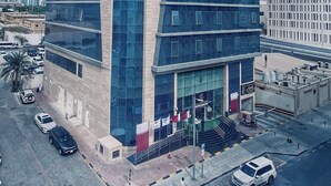 Ein modernes Hochhaus mit markantem Eckdesign, großen Fenstern und einem Eingang mit Treppe.
