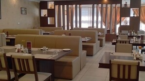 Ein Restaurant mit Sitzgelegenheiten in Form von Boxen und Tischen, einige mit floralen Tischdekorationen.
