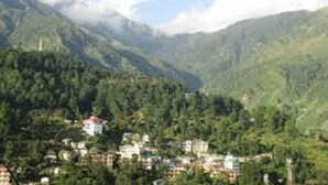 A mountainous landscape with a village nestled among the hills. - New Harmony Inn (Manali)