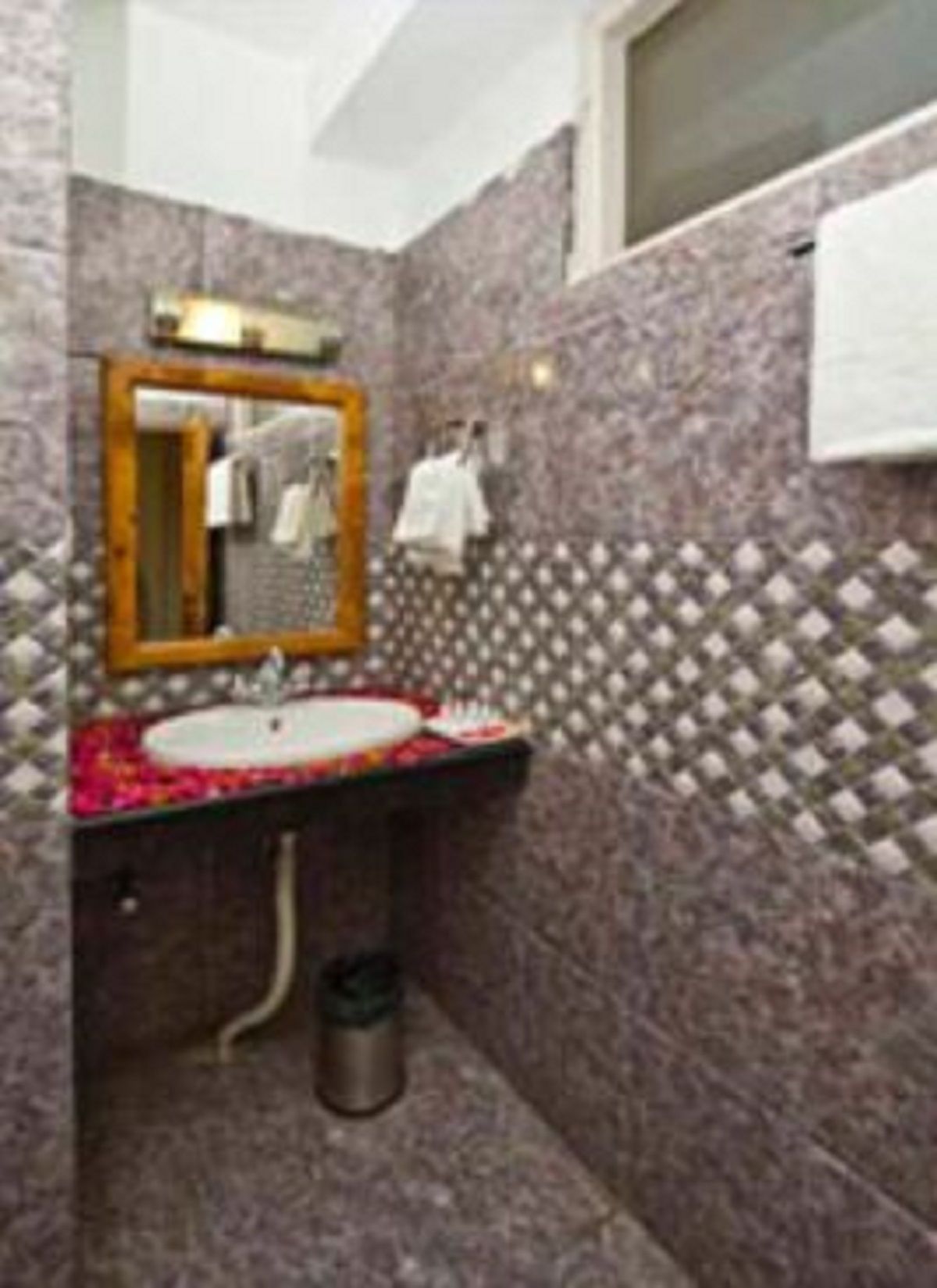 Un baño con lavamanos, espejo y paredes con azulejos.