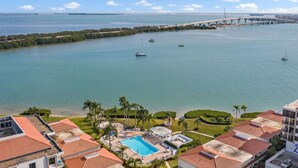 A coastal hotel with a swimming pool, beachfront view, and a bridge in the background. - Penthouse Paradise with Amazing Views: 2BD, 2BA - (Isla Del Sol)