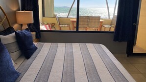 A bedroom with a large bed, a view of the sea, and a balcony with chairs and a table. - Spectacular  Ocean Front 1 Bedroom Villa in Golf community, Pal mas Del Mar  (Palmas Del Mar)