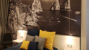 A bedroom with a large bed, a nightstand, and a wall-mounted lamp. - Beverello Rooms (Naples)