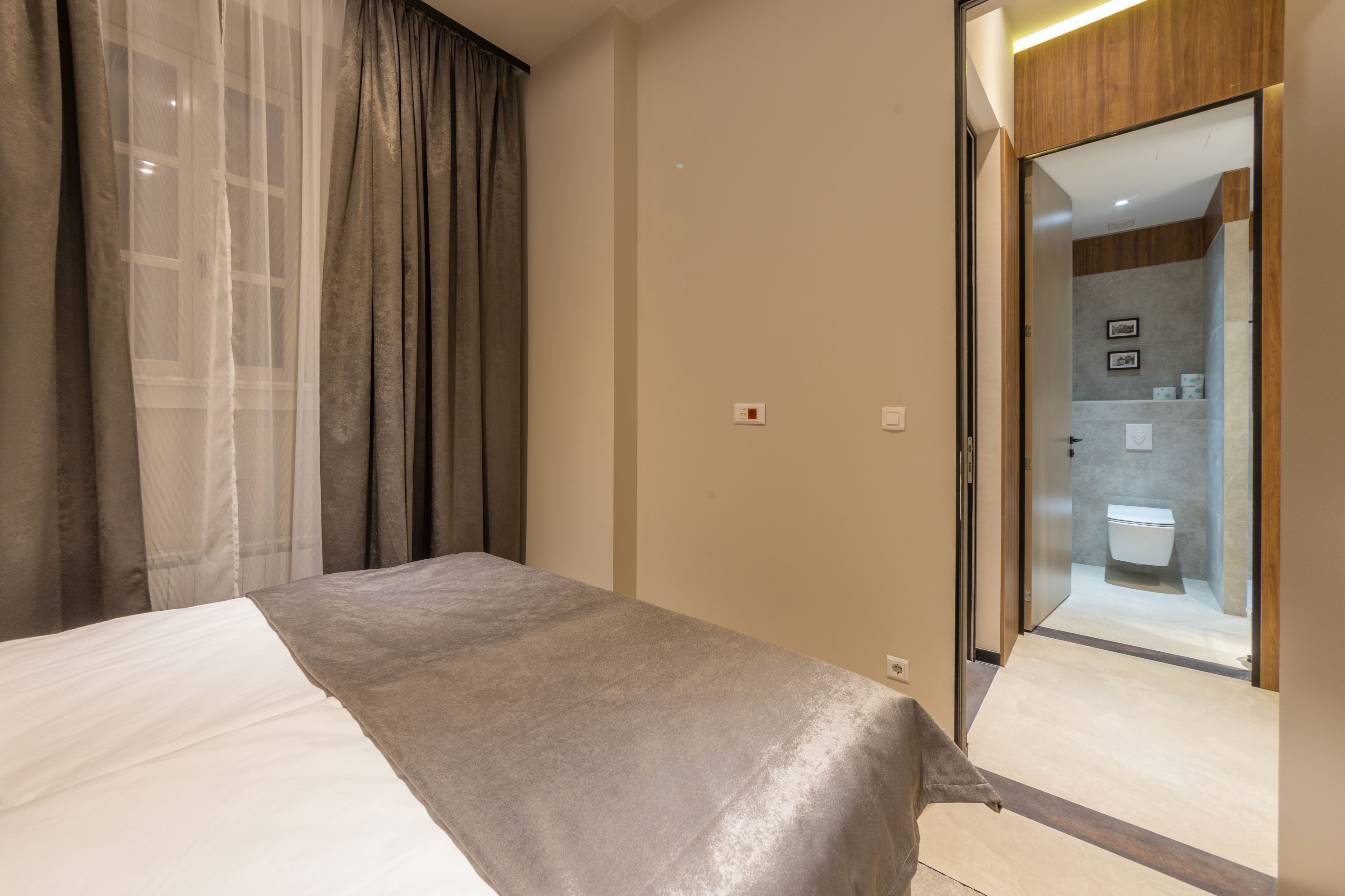 A modern hotel room with a bed, a large mirror, and a view into the bathroom.