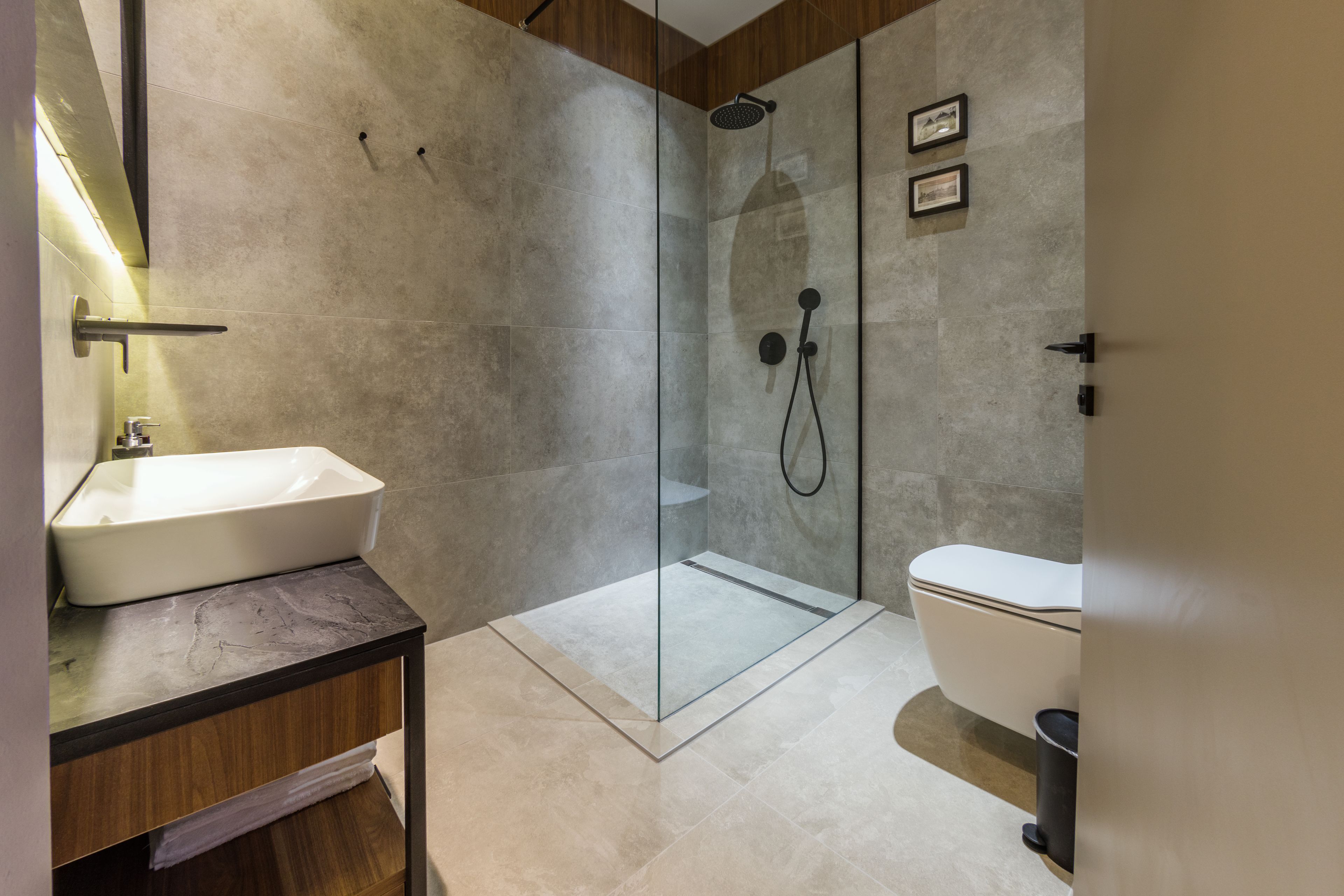 A modern bathroom with a glass-enclosed shower, a white sink, and a toilet.