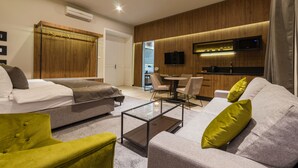 A modern living room with a sofa, a green armchair, a glass coffee table, and a TV mounted on the wall. - Dezman Luxury Center (Zagreb)