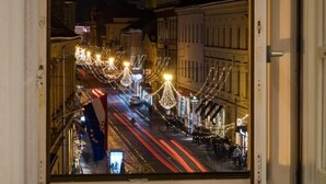 A window view of a city street at night with illuminated buildings and street lights. - Dezman Luxury Center (Zagreb)