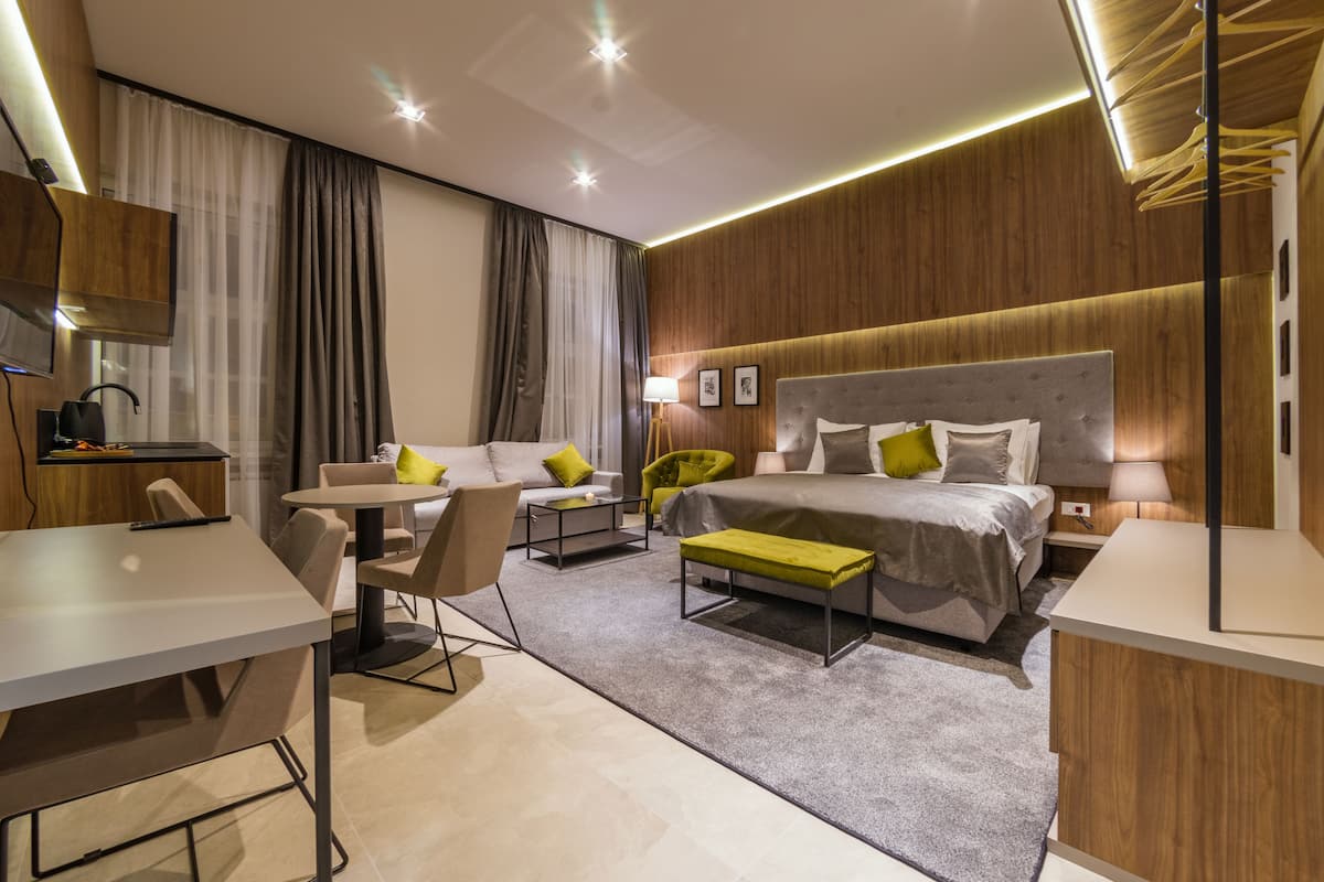 Ein modernes Hotelzimmer mit einem Bett, einem Schreibtisch, einem Sessel, einer Couch und einem kleinen Tisch.