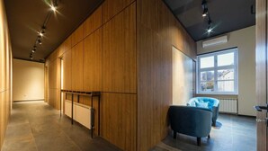 A modern interior with a wooden partition, a radiator, a blue armchair, and a window with a view. - Dezman Luxury Center (Zagreb)