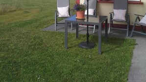 An outdoor patio with a table and chairs, a red umbrella, and a view of the countryside. - Tullaleagan Guesthouse (Oughterard)