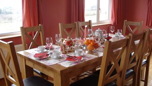 A dining table set with chairs, a floral tablecloth, a fruit bowl, and a teapot. - Tullaleagan Guesthouse (Oughterard)