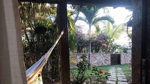 A garden with a hammock, stone wall, and potted plants. - Casa Geribá (Búzios)