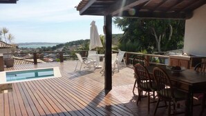 A wooden deck with a pool, outdoor seating, and a view of the ocean. - Casa Geribá (Búzios)