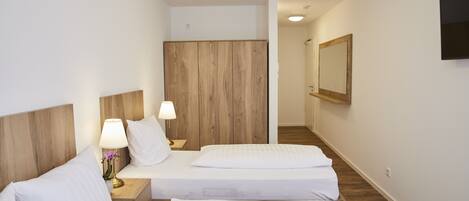 Una habitación de hotel con dos camas, un cabecero de madera, una mesita de noche con una lámpara y un espejo en la pared.