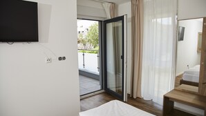 A hotel room with a bed, a TV mounted on the wall, a wooden bench, a sliding glass door leading to a balcony, and a mirror on the wall. - Lothringer Hof (Saarlouis)