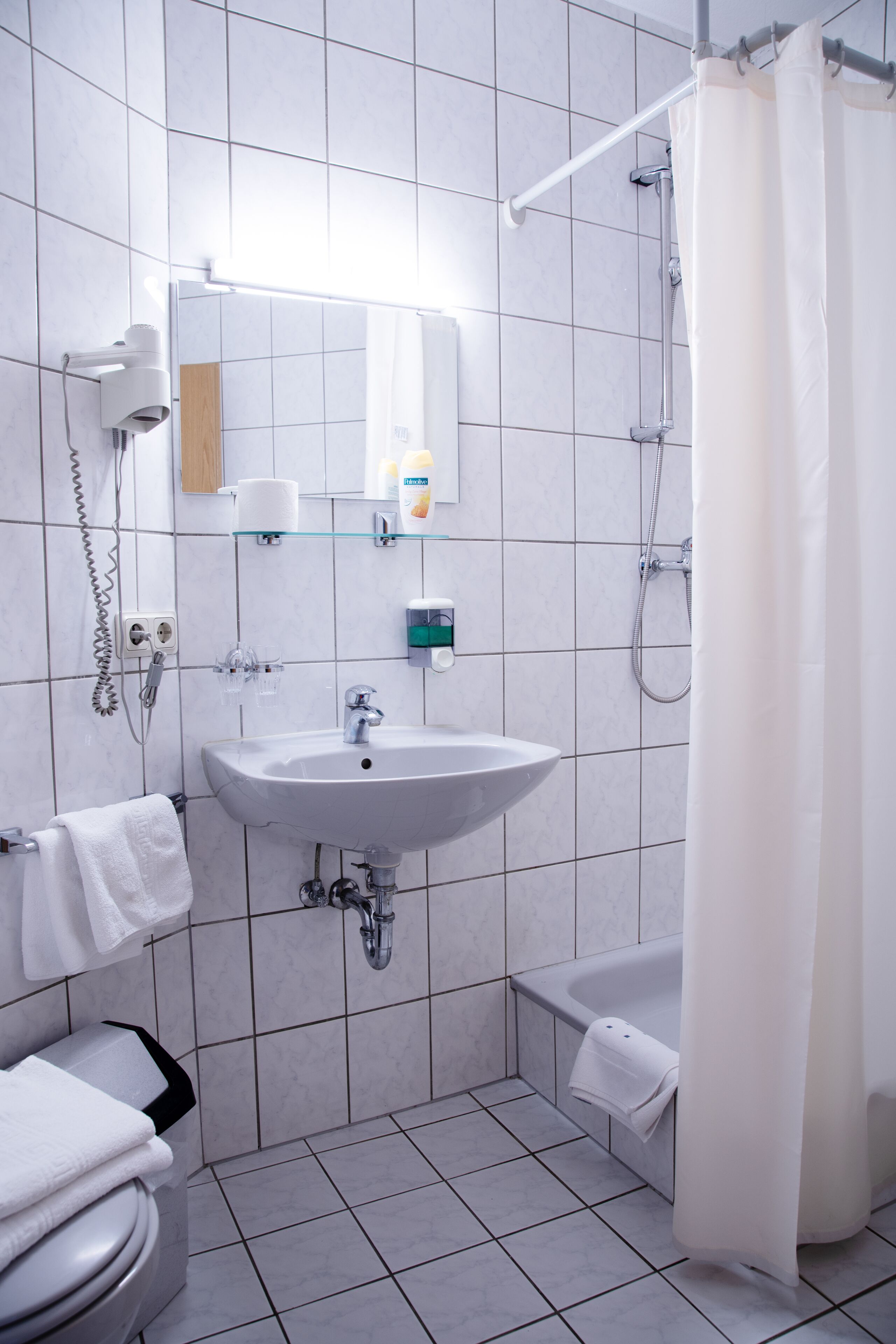 Un baño moderno con lavamanos, espejo y ducha blancos.