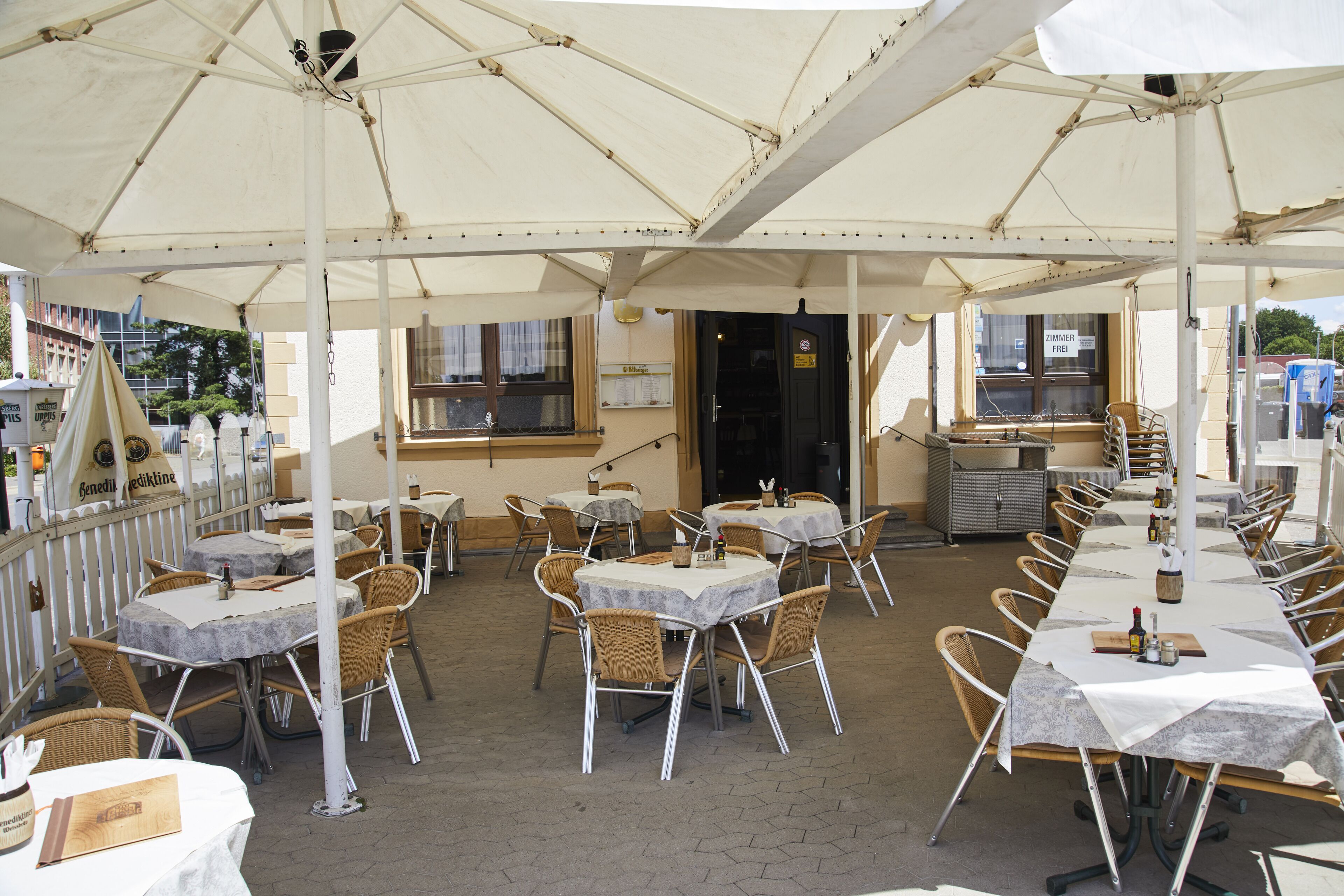 Un área de comedor al aire libre con mesas y sillas bajo una gran carpa.