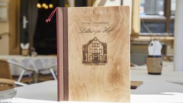 A wooden book with a house illustration and text reading "Hotel Restaurant Lothringer Hof".