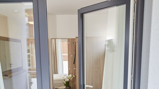 A bedroom with a sliding glass door leading to a bathroom. - Lothringer Hof (Saarlouis)