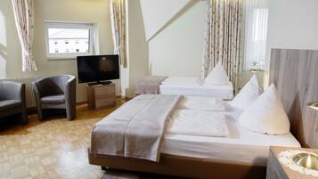 A hotel room with a bed, a TV, a chair, and a window.