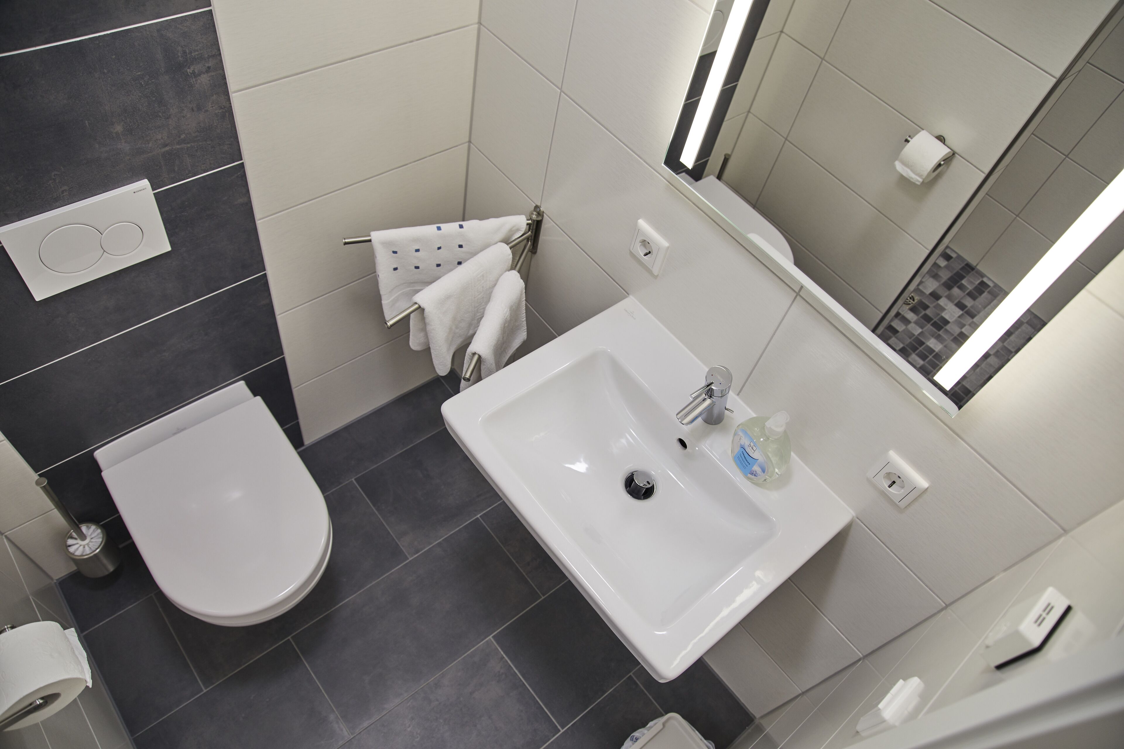 Une salle de bain moderne avec un lavabo blanc, des toilettes et un porte-serviettes.