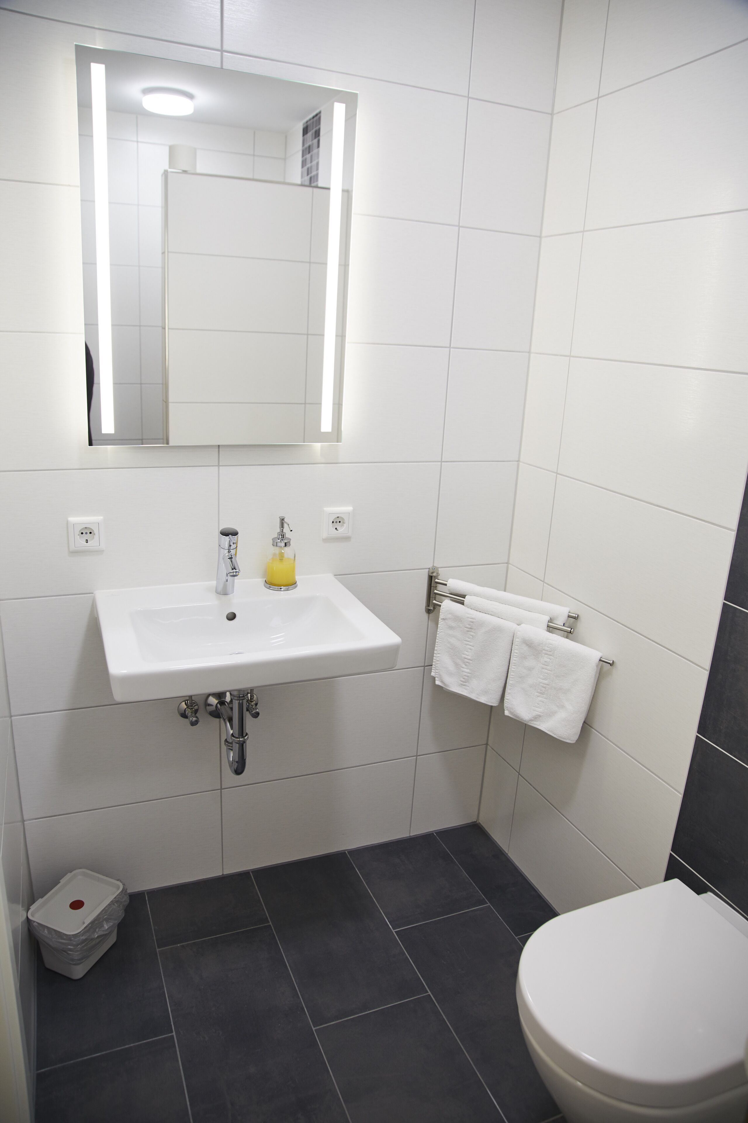 A bathroom with a white sink, mirror, and toilet.
