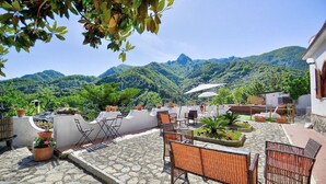 A patio with outdoor seating, potted plants, and a view of mountains.