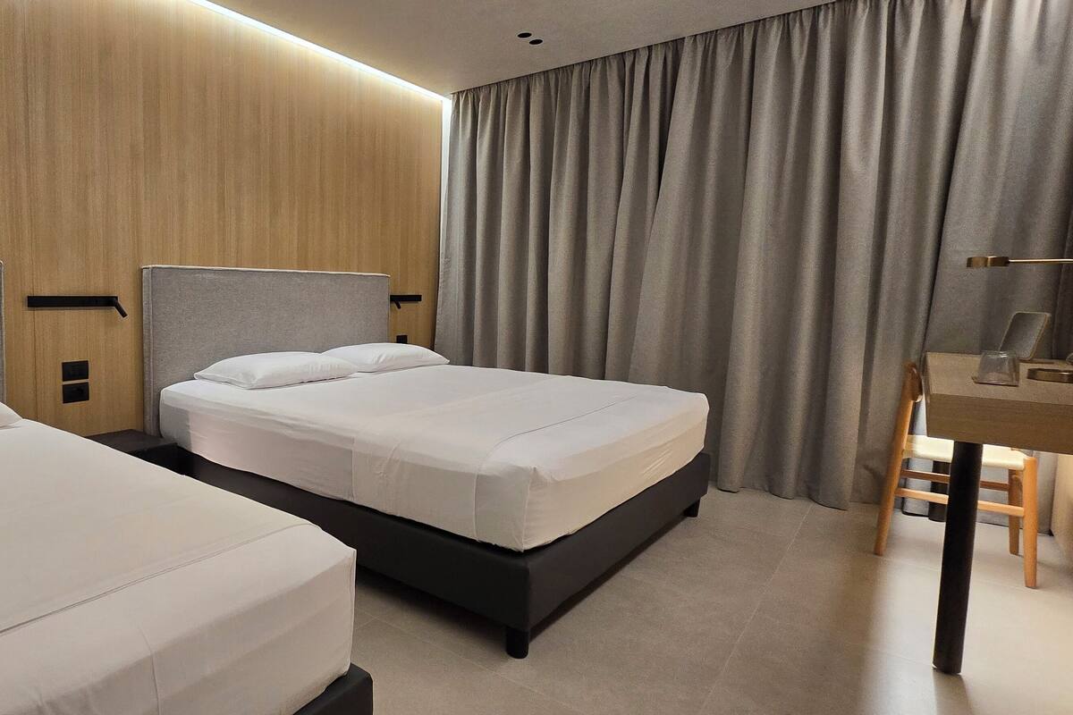 A hotel room with two beds, a desk, and a chair.
