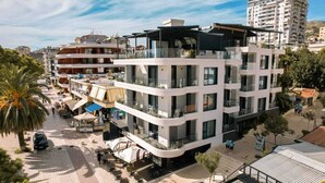 A multi-story hotel with balconies, outdoor seating, and a pool area. - Lion Gate Hotel (Sarandë)