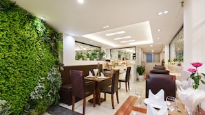 Un restaurante con pared verde, mesas y sillas de madera.