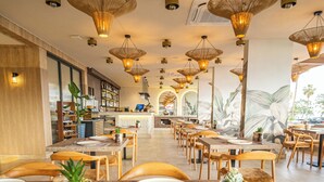 Un restaurante con una larga barra, varias mesas y lámparas colgantes.