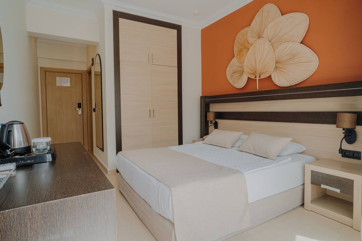 A hotel room with a bed, a nightstand, a coffee maker, and a wall with a large floral design.
