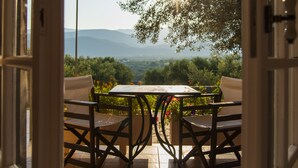 An open door leading to an outdoor patio with a table and chairs, overlooking a scenic landscape with mountains and trees. - Penelope Dream Pool Villa (Kefalonia)