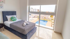 A bedroom with a bed, a large window, and a view of a swimming pool. - Coral Elite Residence 12. New luxury villa with private pool and hot tub jacuzzi (Paphos)